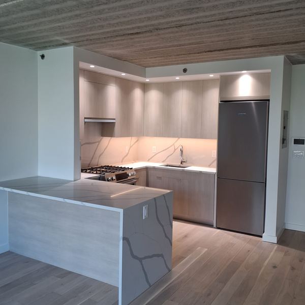 Light oak kitchen with marble waterfall peninsula by CABINX